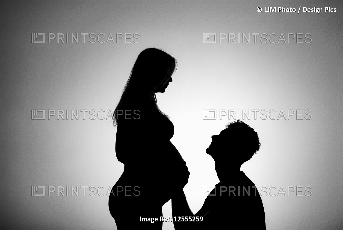 A silhouette in a studio of a couple who are having a baby and the father is ...