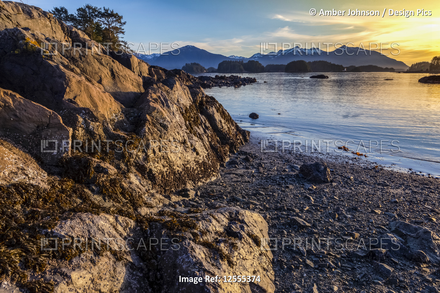 Winter sunset on rocky beach looking out over Crescent Bay; Sitka, Alaska, ...
