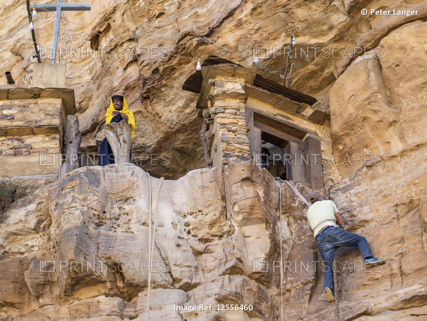 Man climbing on a rope to reach Debre Damo monastery; Tigray Region, Ethiopia