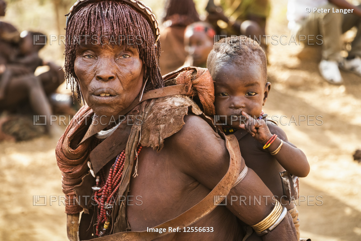 Hamer woman carrying a baby at a bull jumping ceremony, which initiates a boy ...
