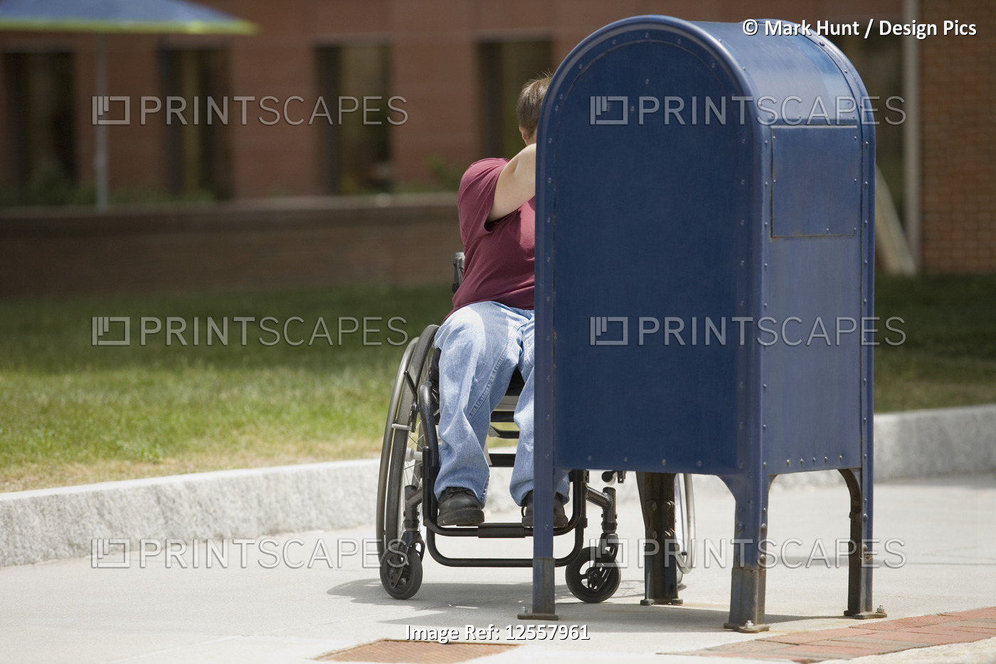 Woman sitting in a wheelchair and putting mail into a mailbox