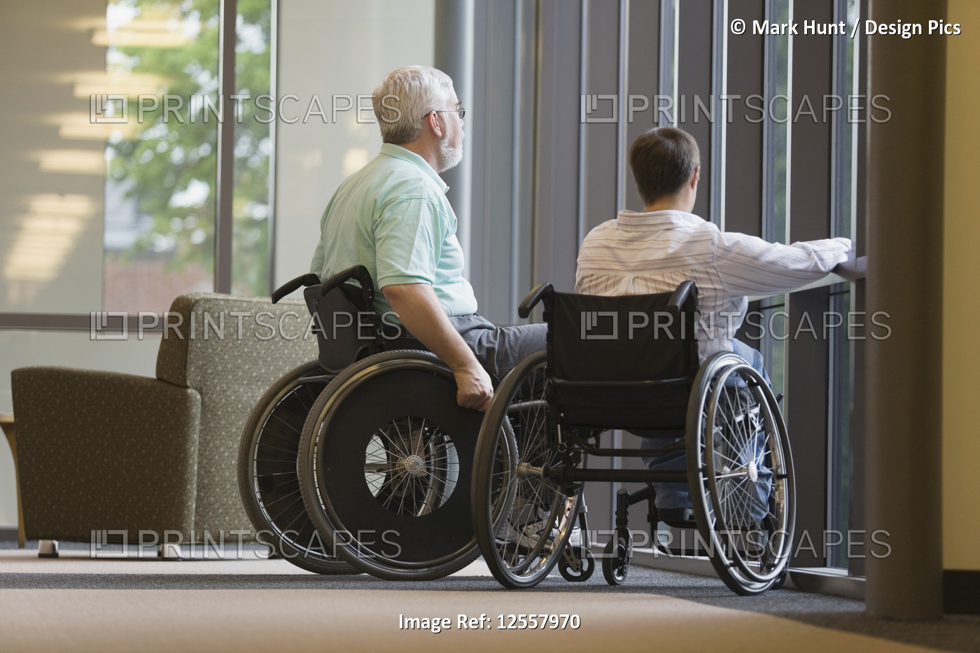 Mature man with Muscular Dystrophy  and a young woman sitting in wheelchairs in ...