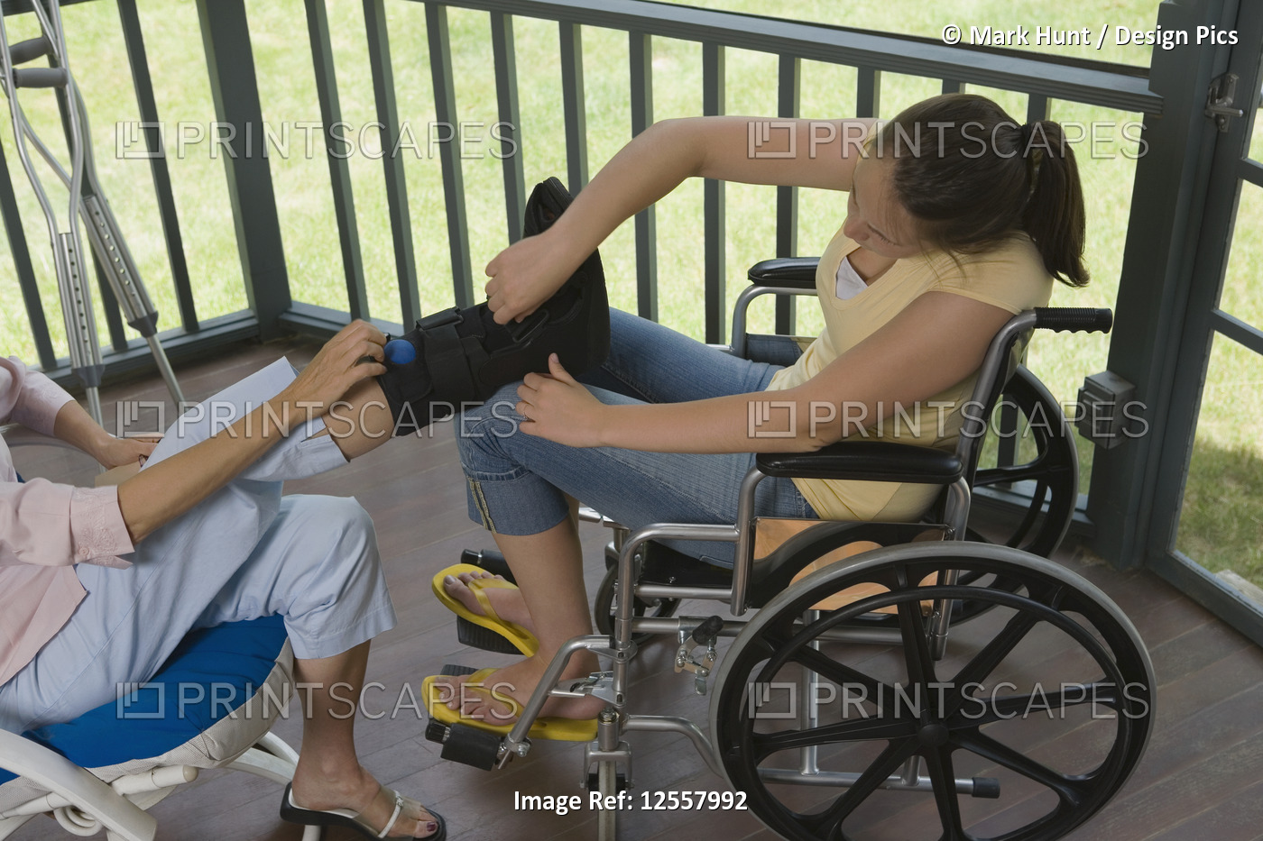 High angle view of a young woman sitting in a wheelchair and adjusting an ...