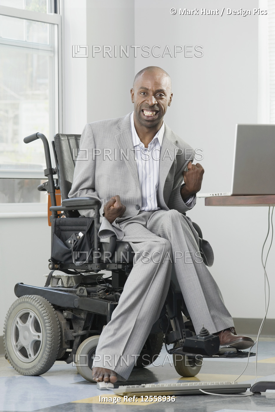 Businessman with Cerebral Palsy working on a computer with his foot