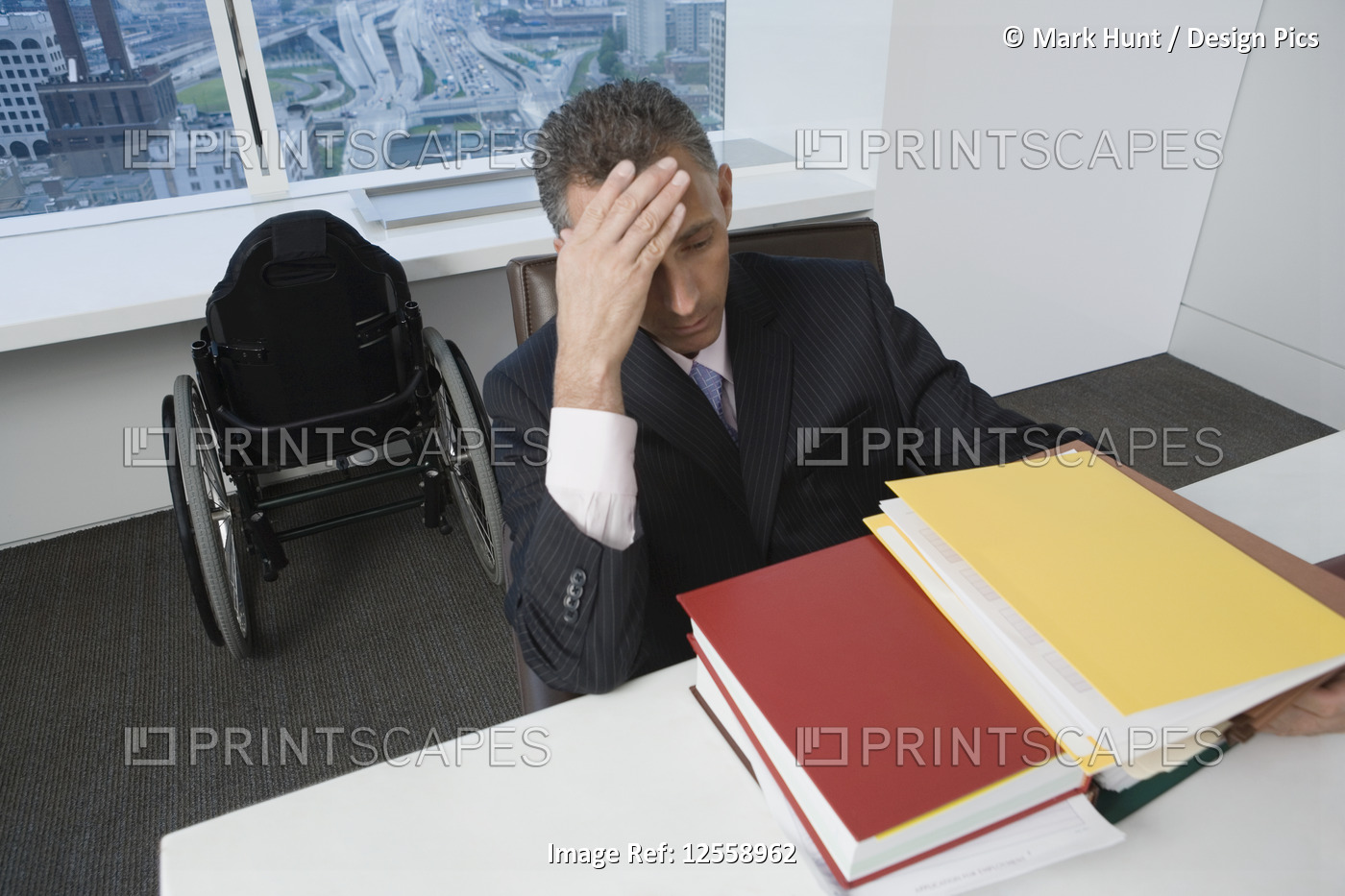 Businessman with a wheelchair looking stressed in office