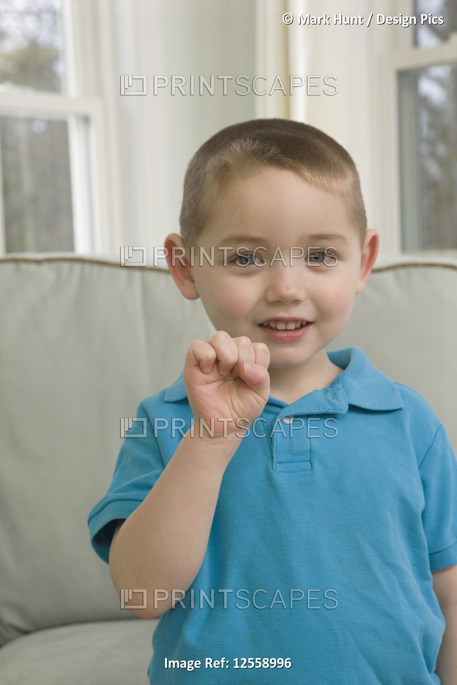 Boy signing the letter 'S' in American sign language