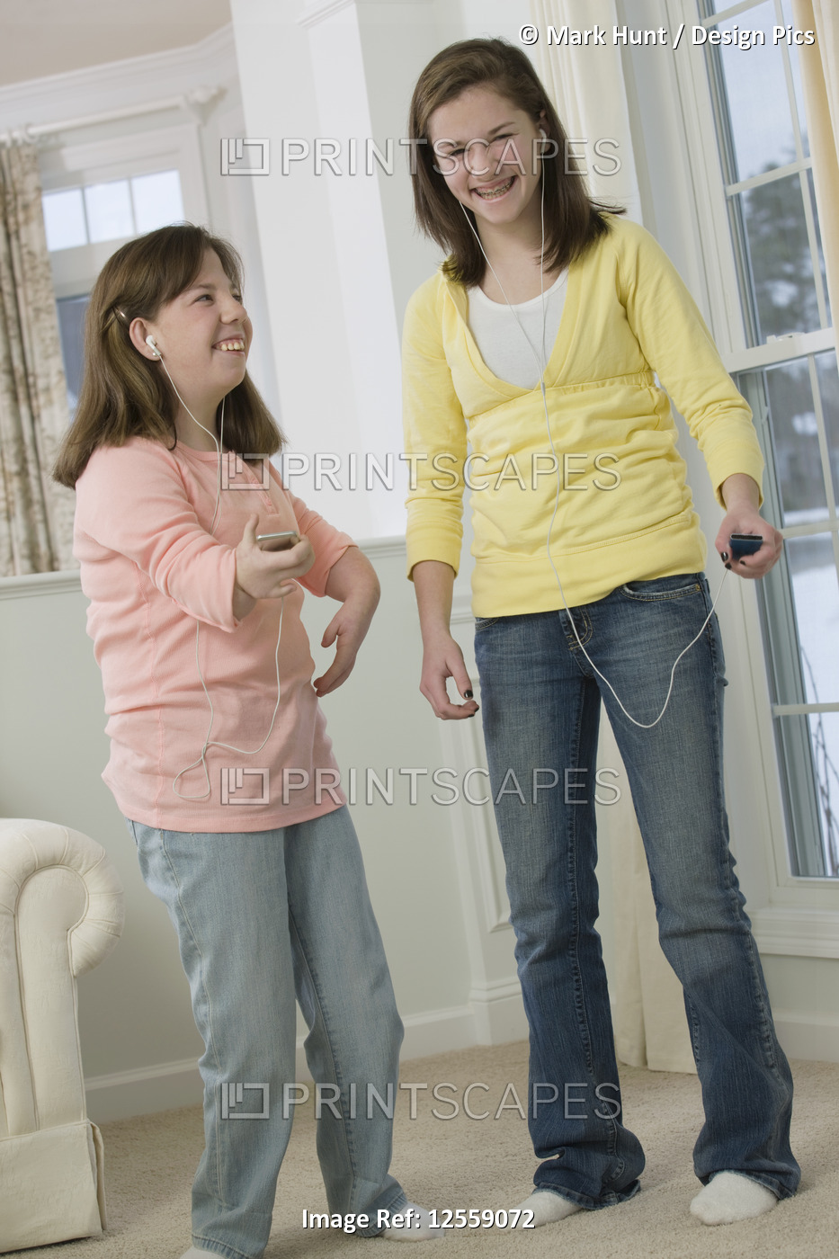 Two teenage girls listening to MP3 players, one with birth defect