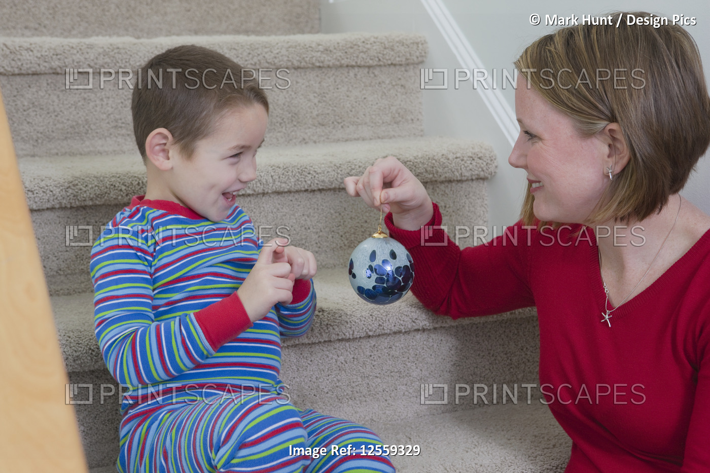 Woman showing Christmas ornament to her son and signing