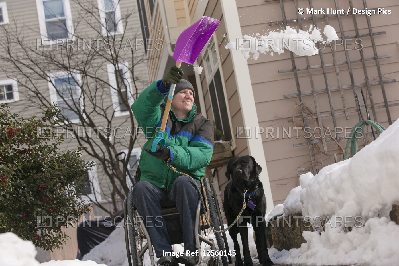 Woman with multiple sclerosis shoveling snow in a wheelchair with a service dog