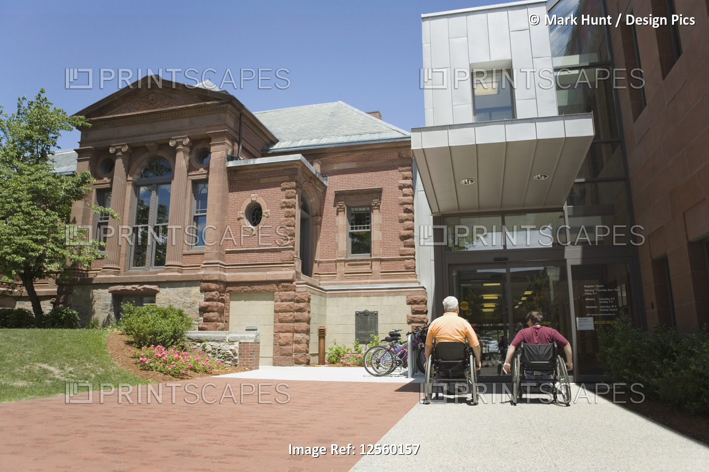 Rear view of two people with Muscular Dystrophy in front of a library building