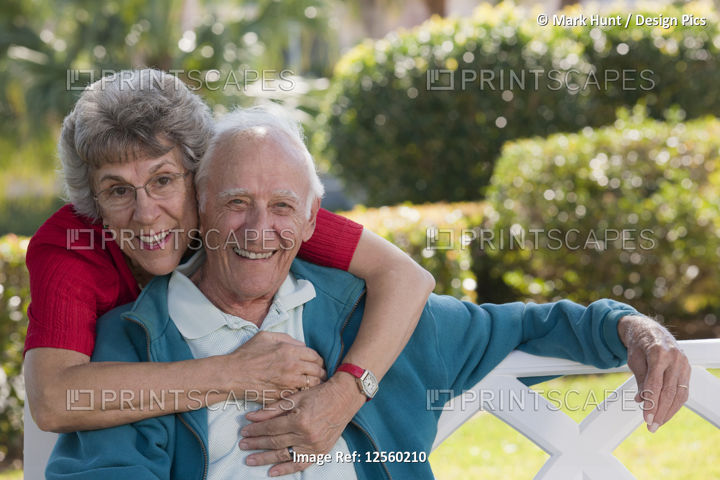 Portrait of a senior woman hugging her husband from behind in a park