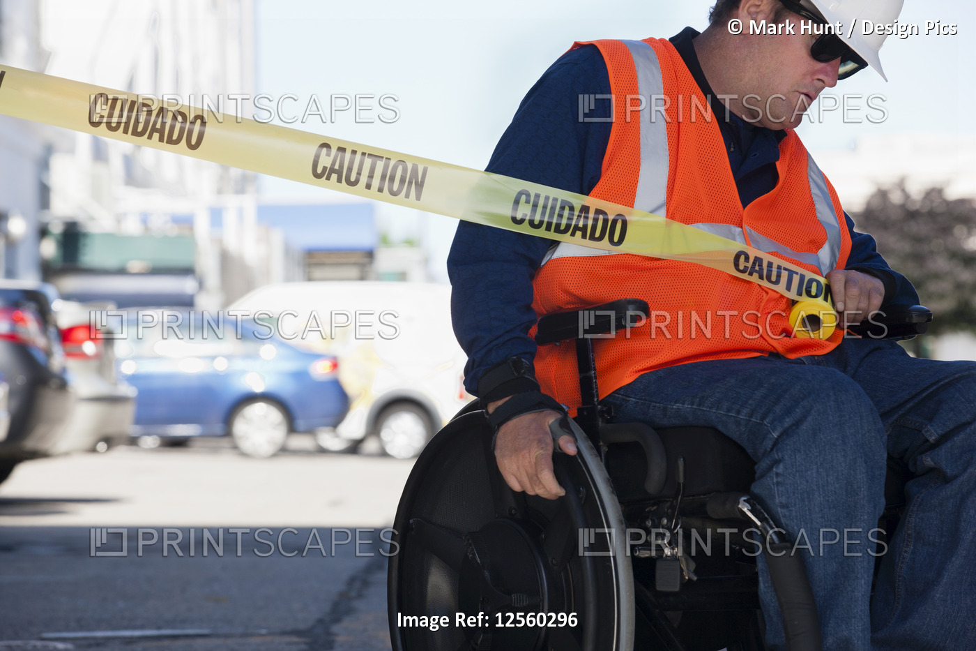 Facilities engineer in a wheelchair pulling caution tape across road