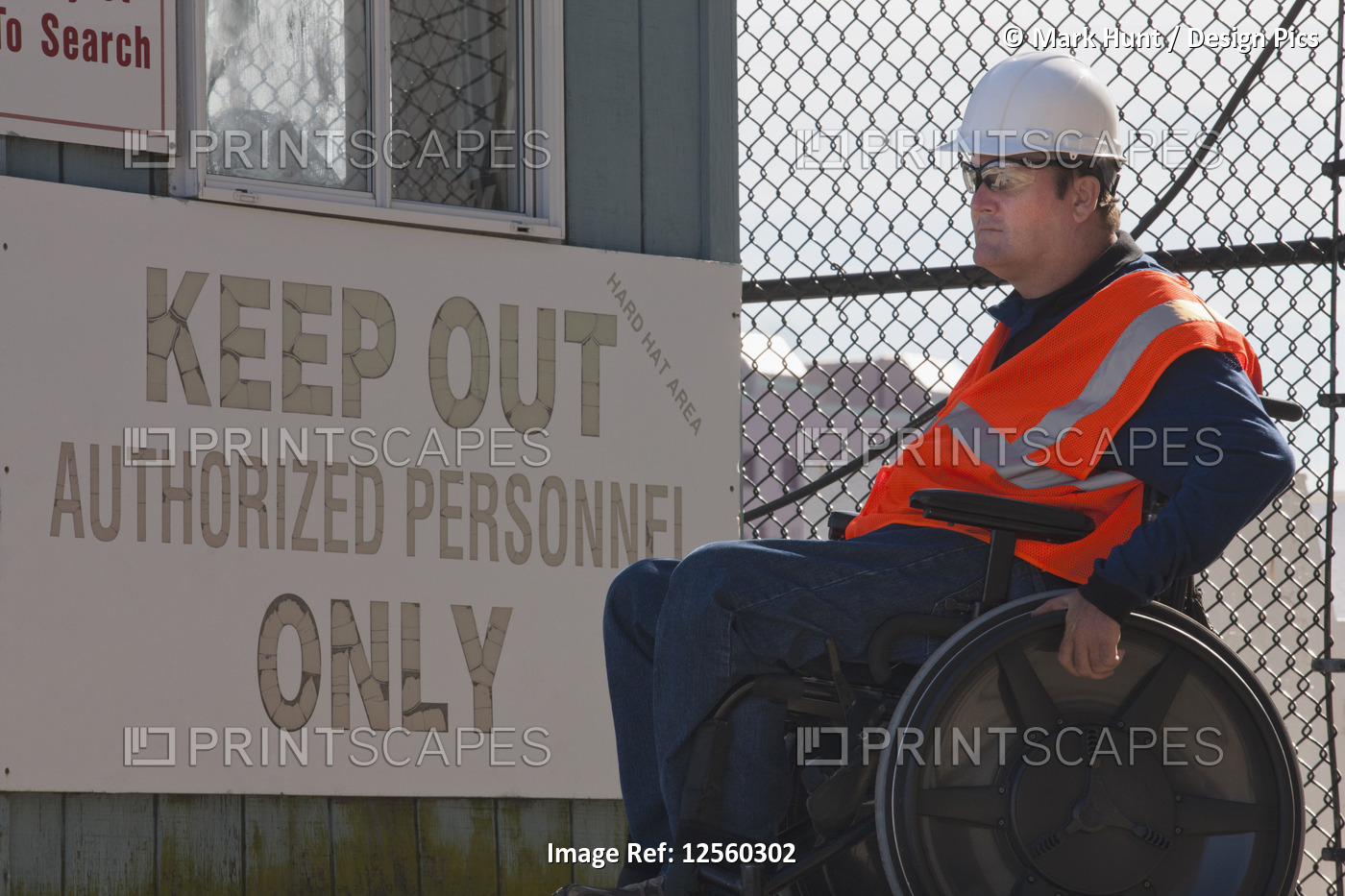 Facilities engineer in wheelchair at guard station entrance to hard hat area
