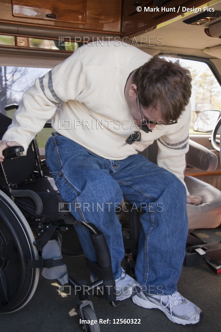Man with spinal cord injury getting into the driver's seat from his wheelchair ...