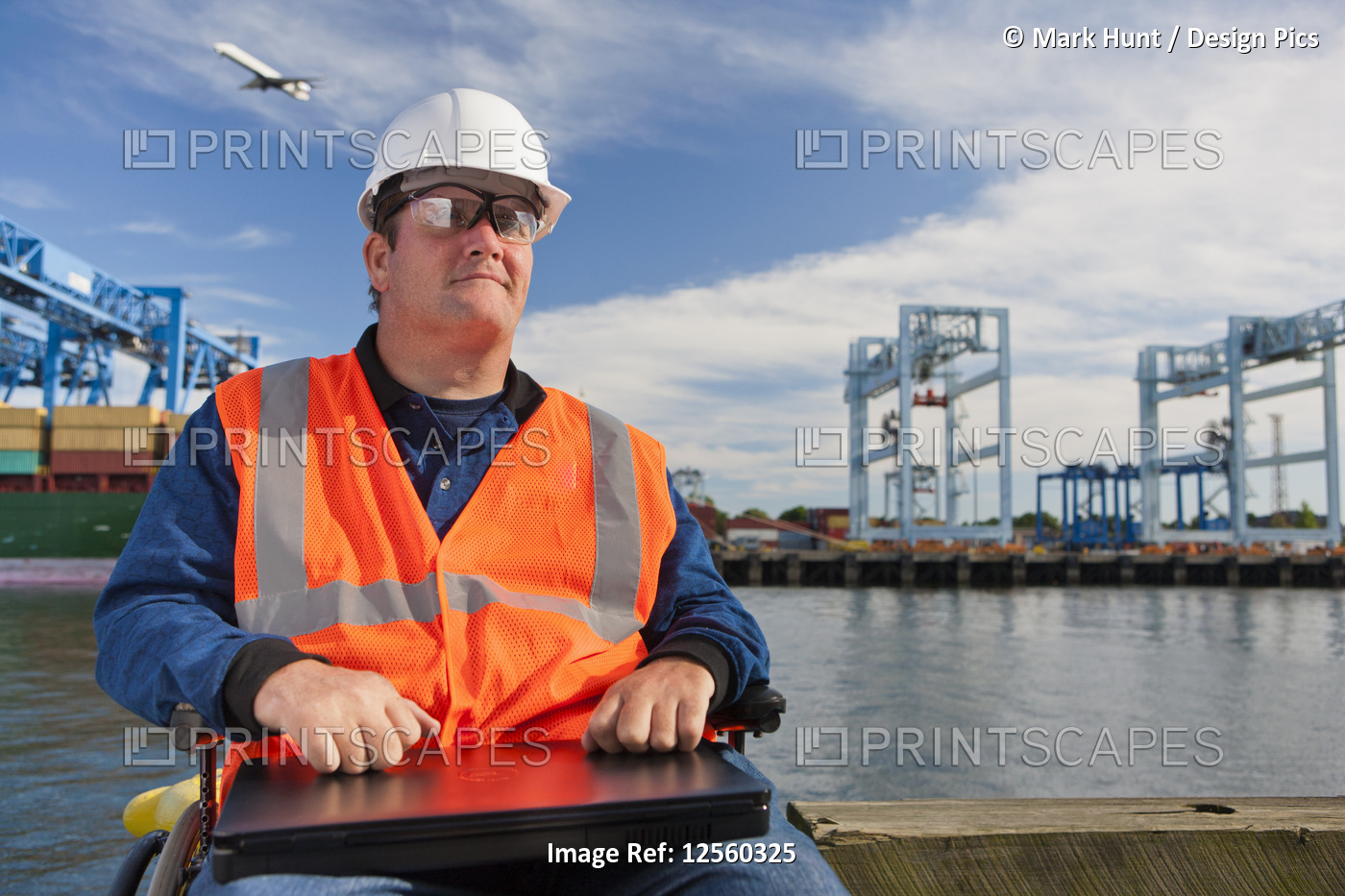 Transportation engineer in wheelchair with a laptop at shipping port