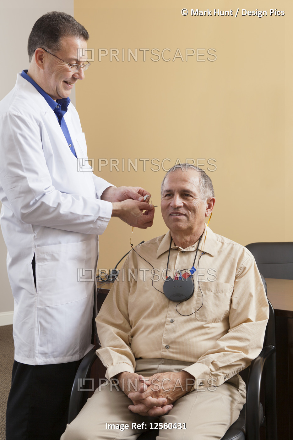 Audiologist inserting behind-the-ear hearing aid into a patient's ear during ...