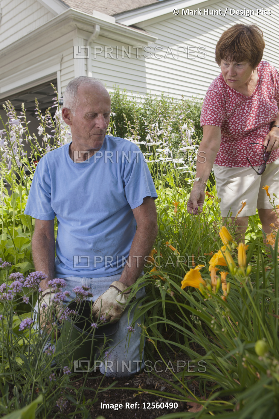 Woman giving advice to her husband about planting flowers in their garden