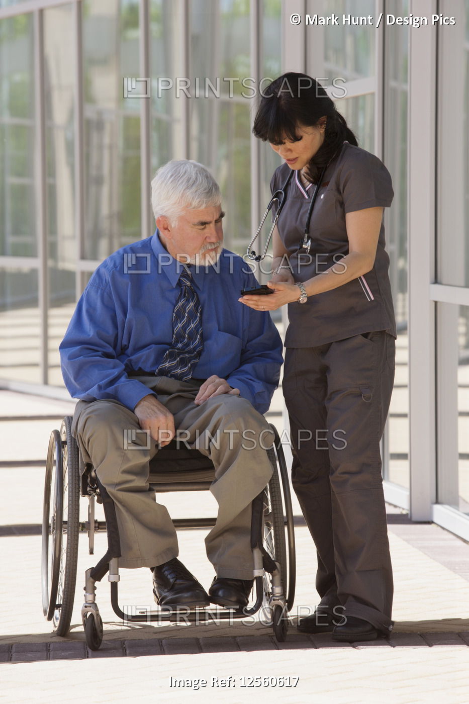 Man with muscular dystrophy and diabetes in his wheelchair talking with nurse ...