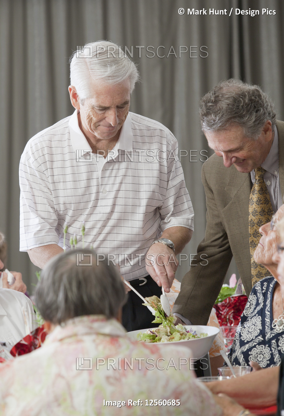 Senior men serving food to their wives