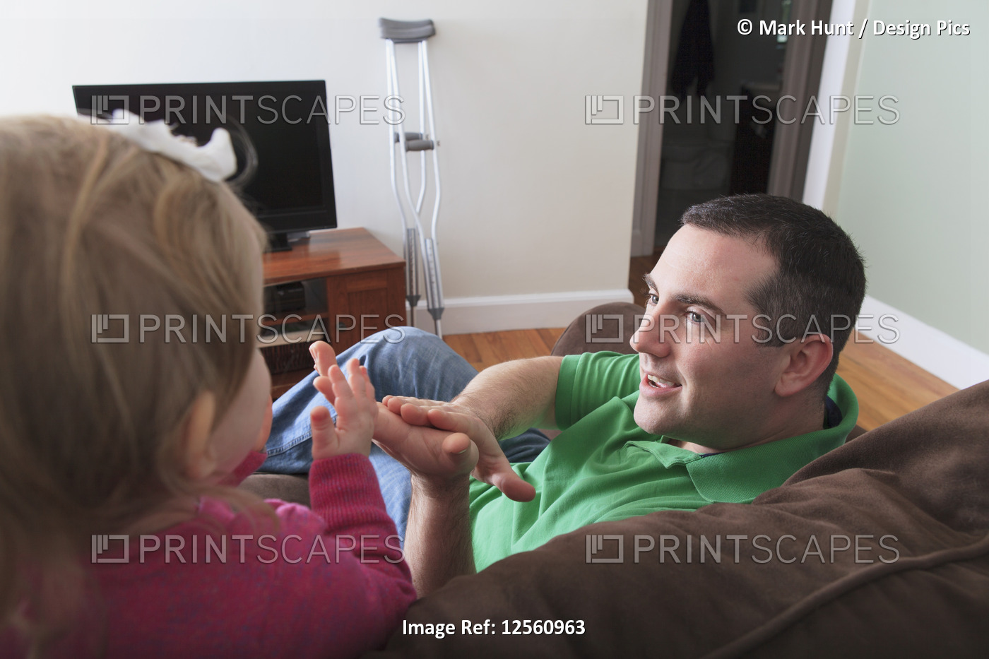 Man after anterior cruciate ligament (ACL) surgery playing with his daughter at ...