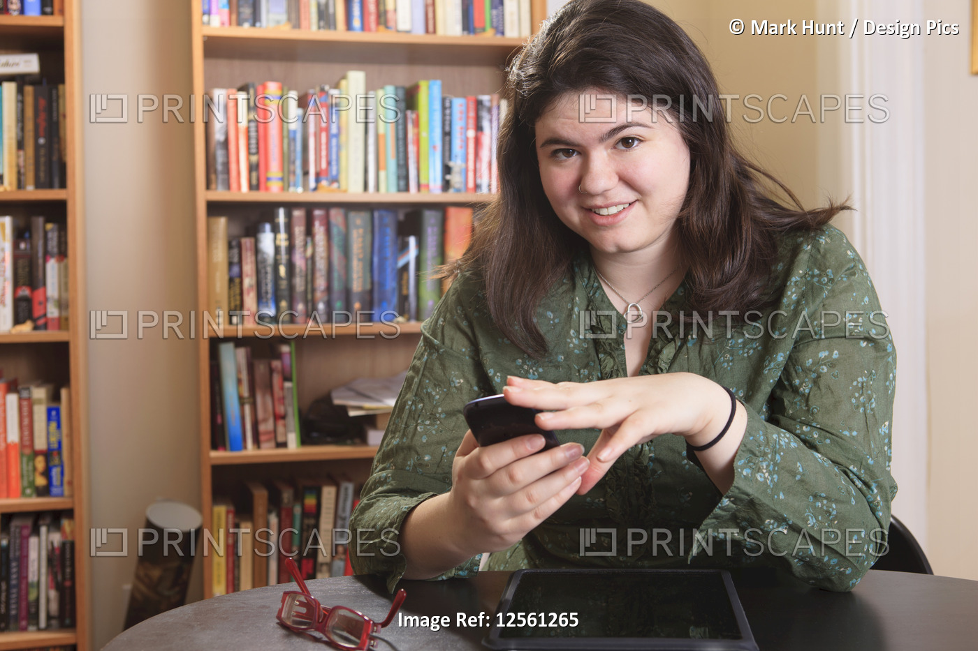 Woman with Asperger syndrome working with her smart phone and tablet from home ...