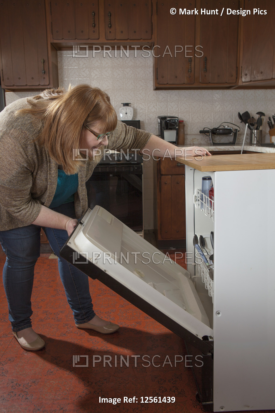 Woman who is legally blind loading the dishwasher in her kitchen