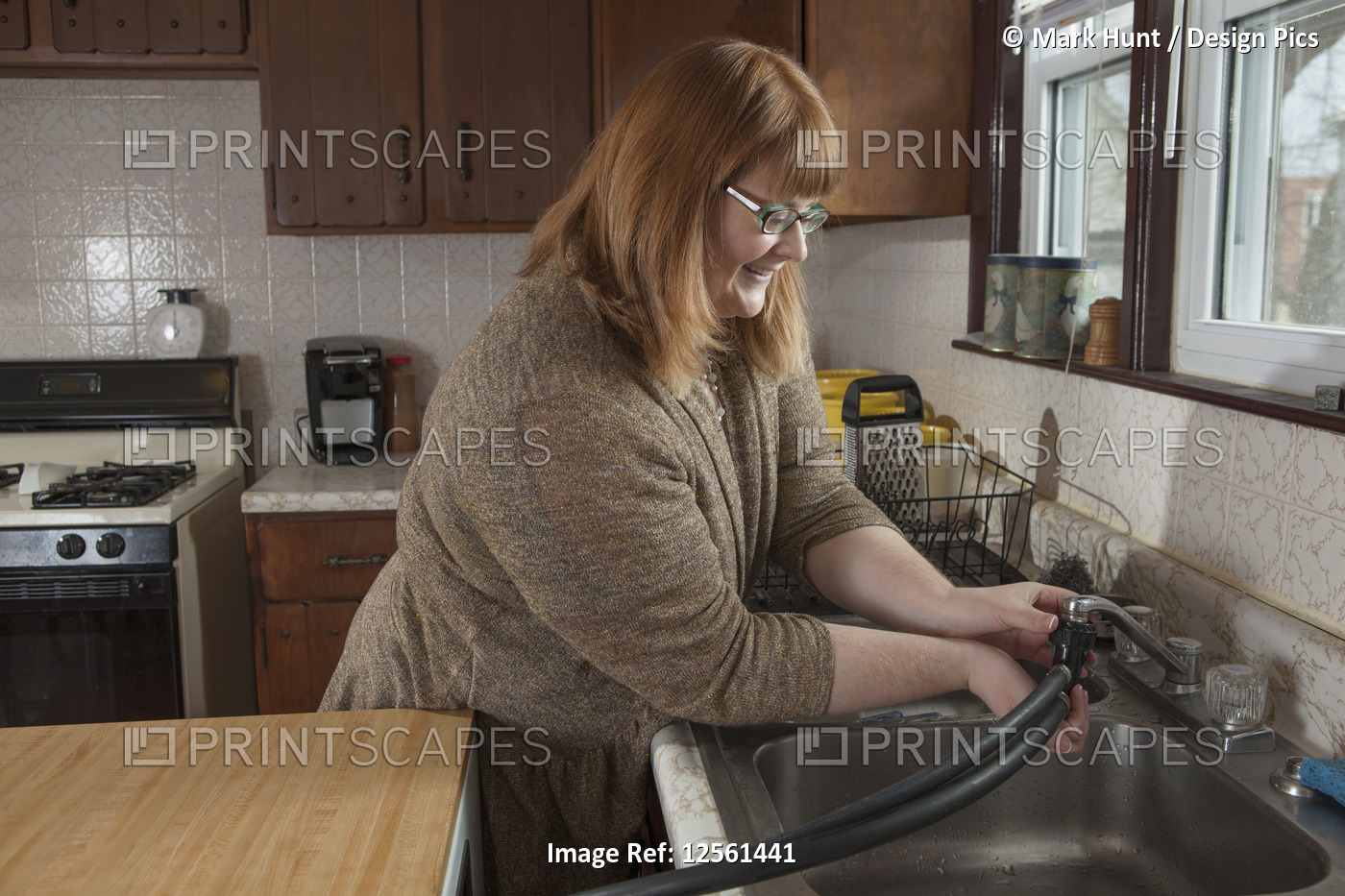 Woman who is legally blind hooking up the portable dishwasher in her kitchen