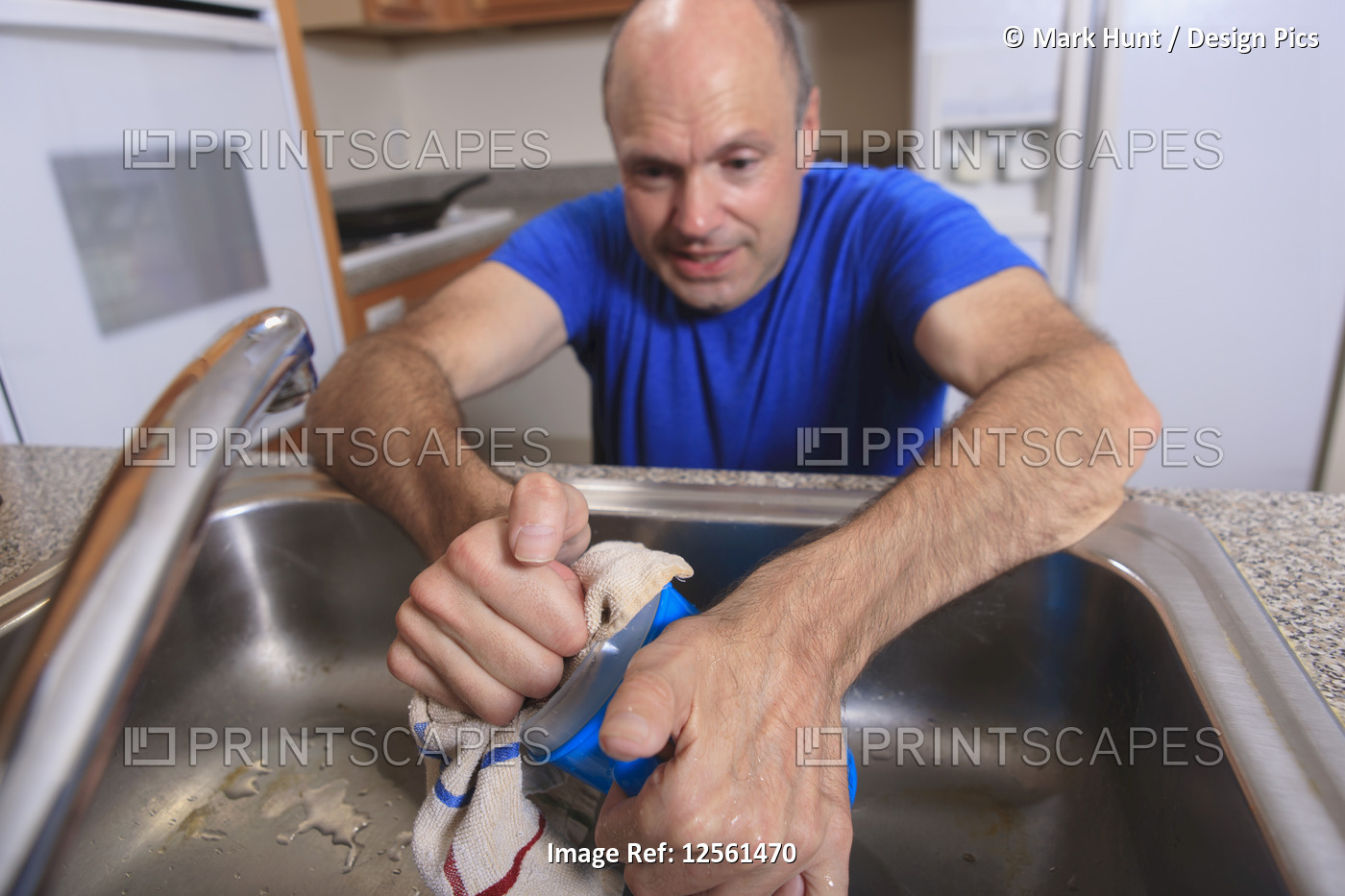 Man with Friedreich's Ataxia and deformed hands washing dishes in his kitchen ...