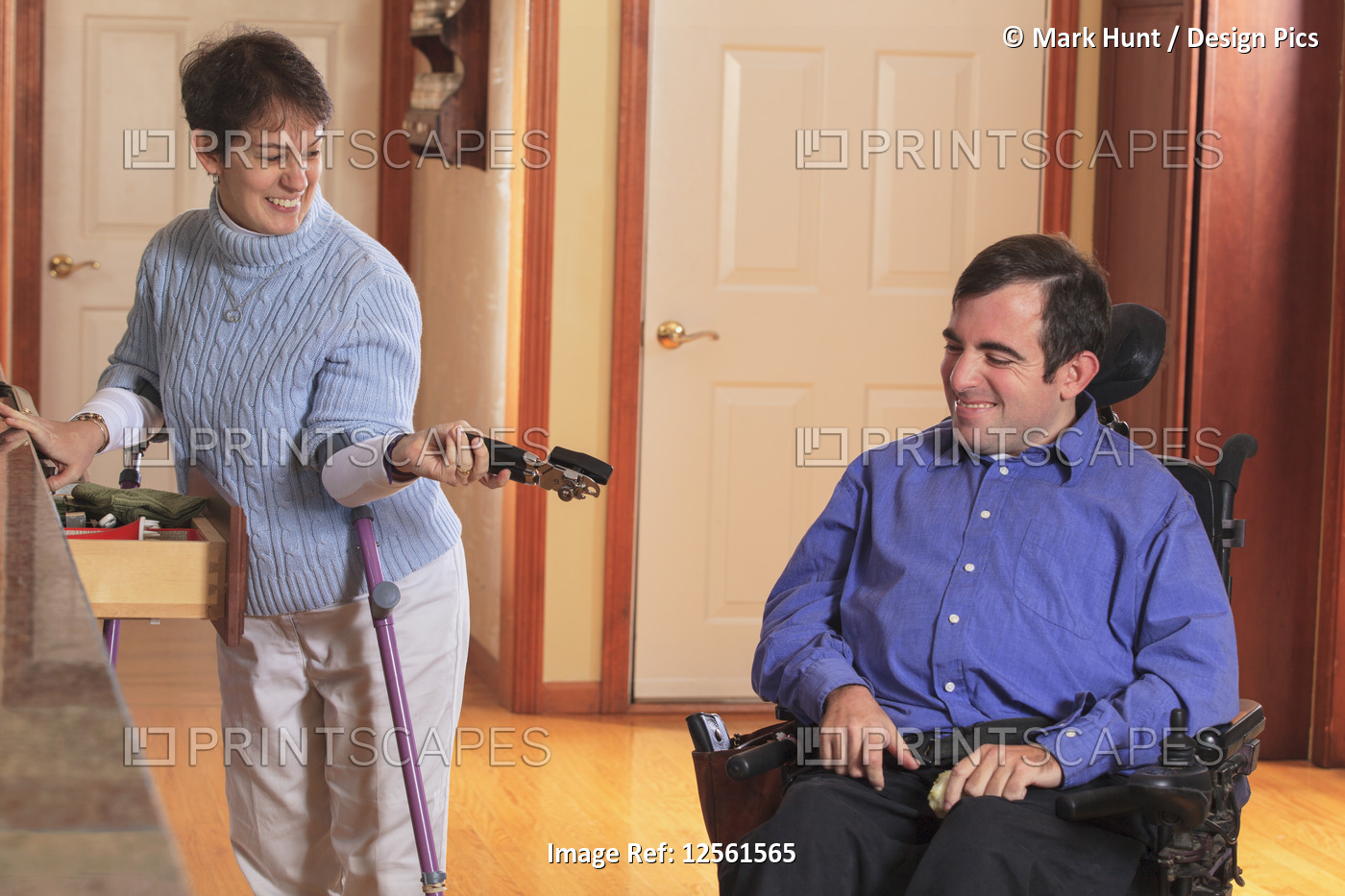 Woman with Cerebral Palsy using crutches and giving a can opener to her husband ...