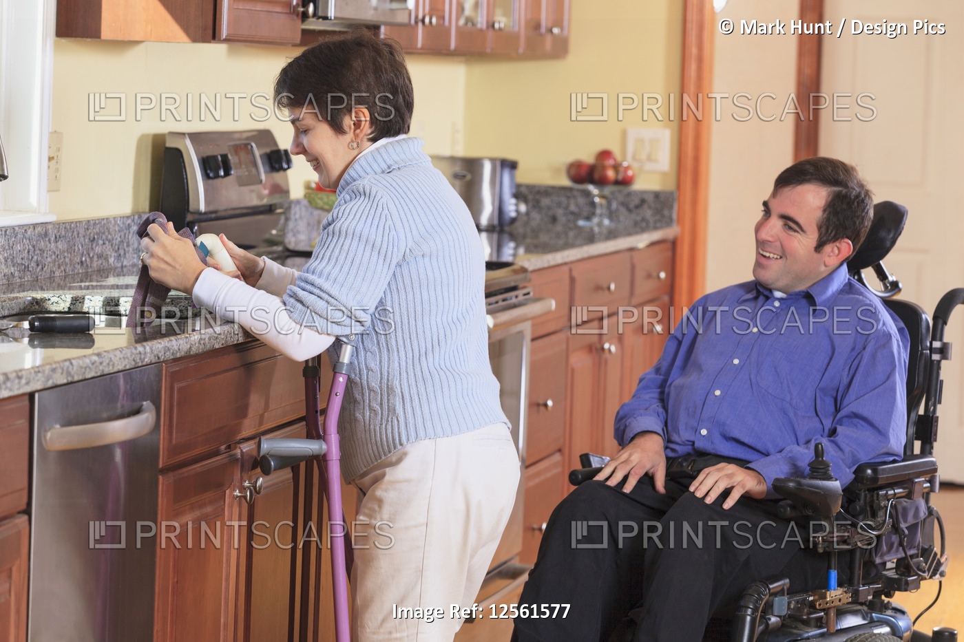 Woman with Cerebral Palsy using crutches and working in her kitchen while ...
