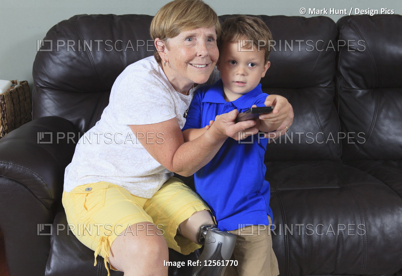 Grandmother with a prosthetic leg with her grandson with a remote control