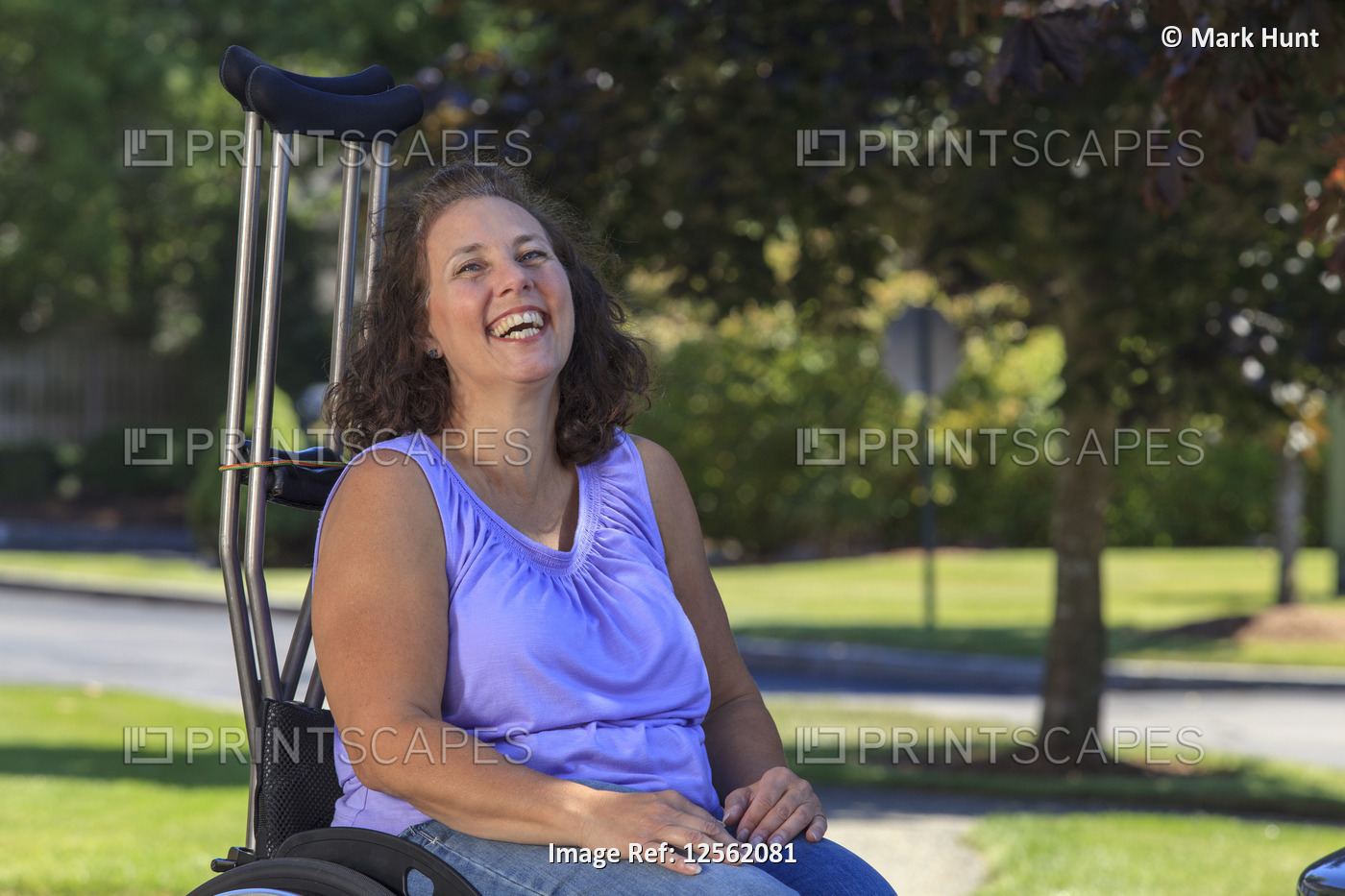 Woman with Spina Bifida laughing while sitting in wheelchair with crutches
