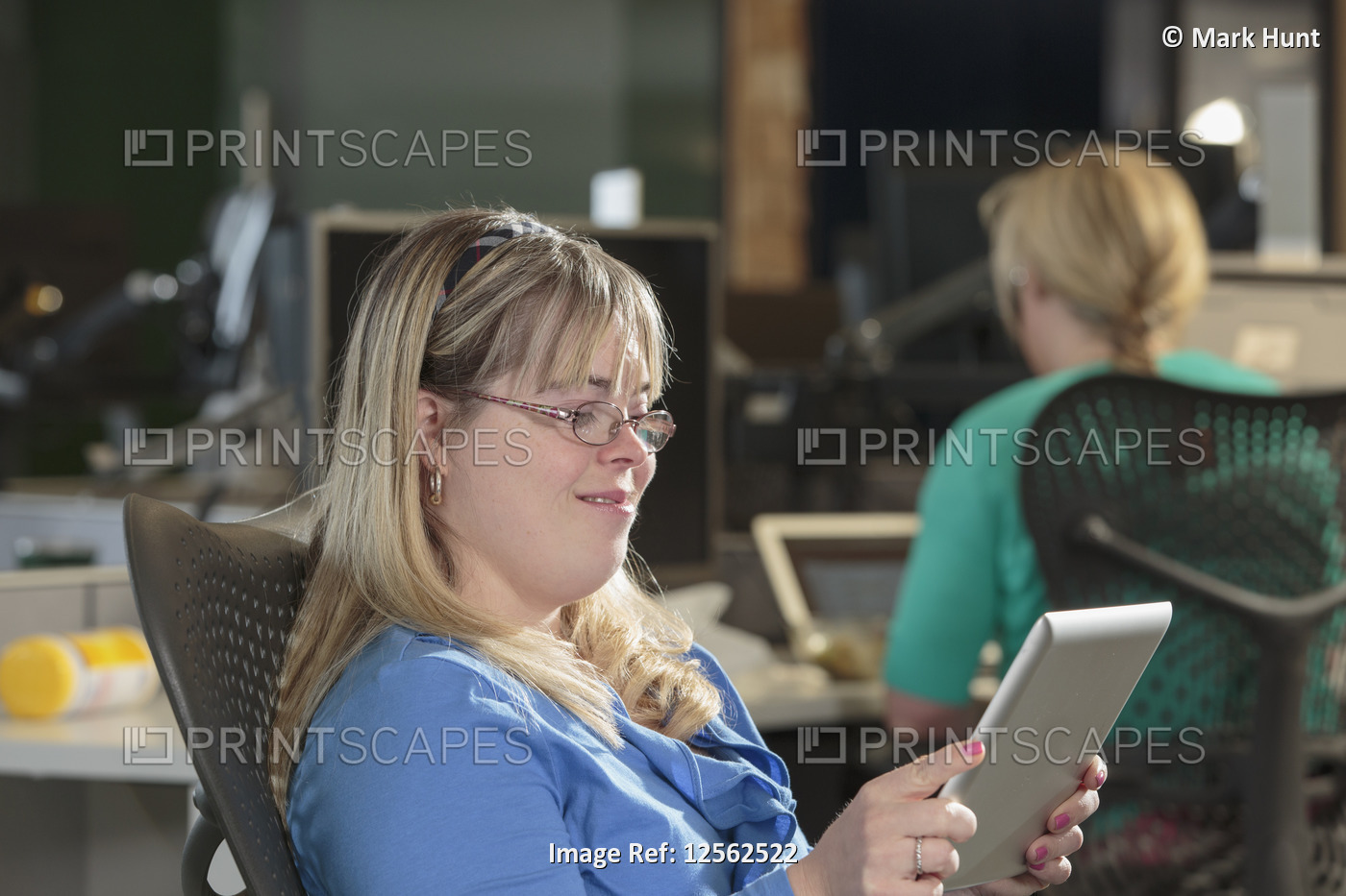 Young woman with Down Syndrome working on a tablet in an office
