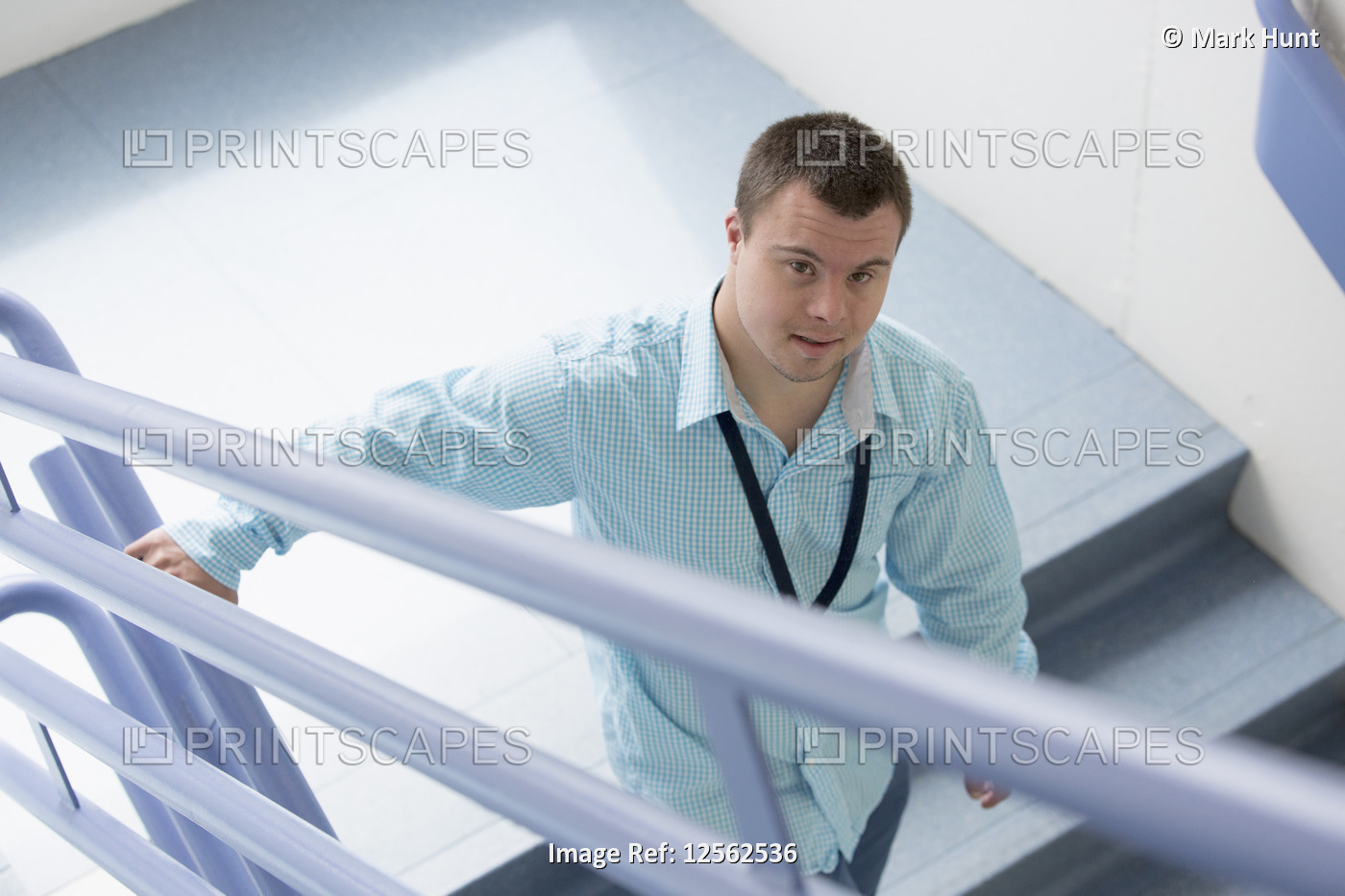 Young man with Down Syndrome working as a hospital aid on the stairwell
