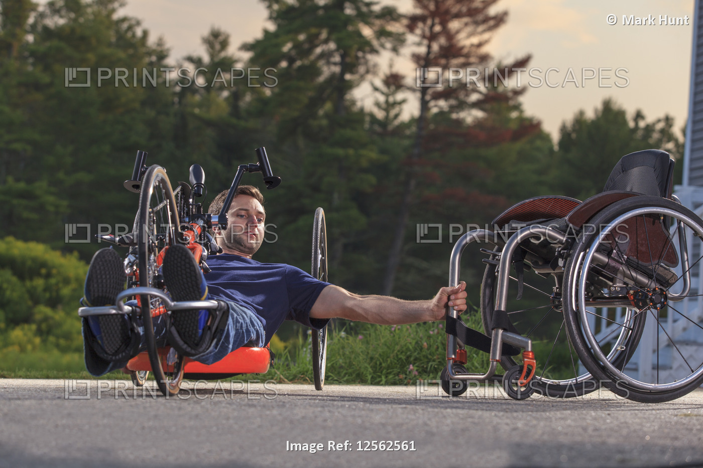 A man with a disability lays on an adaptive bicycle while holding onto his ...