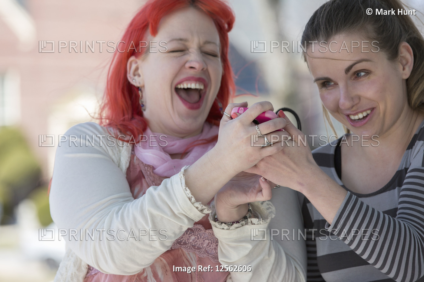 Blind young women using assistive technology on their cell phones and laughing