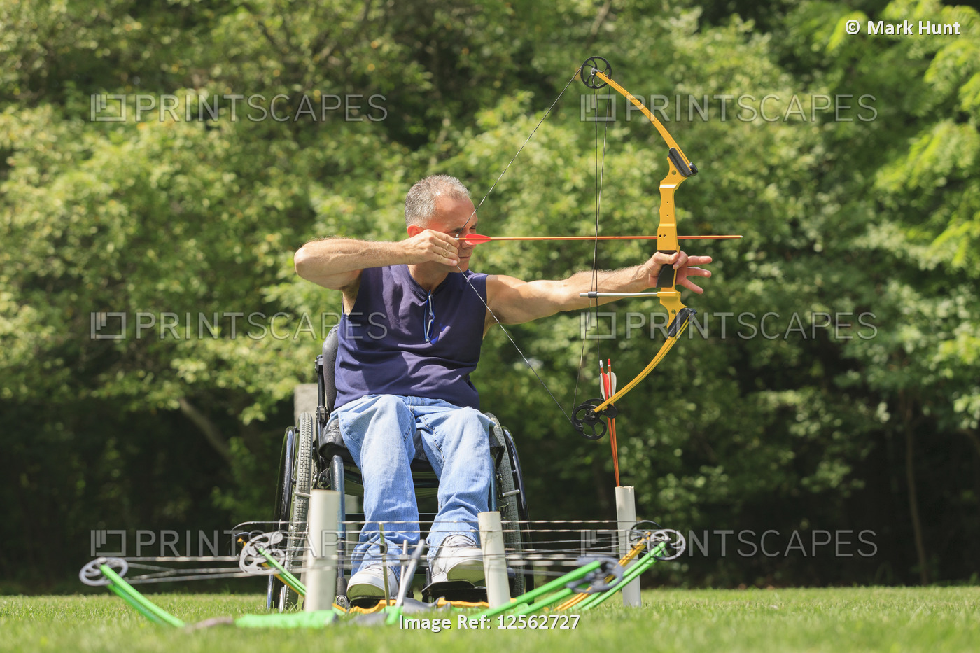 Man with spinal cord injury in wheelchair aiming his bow and arrow for archery ...