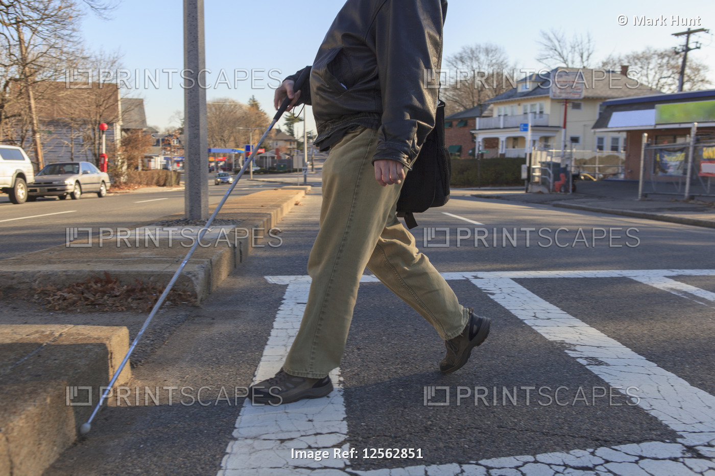 Man with congenital blindness crossing the street using his cane