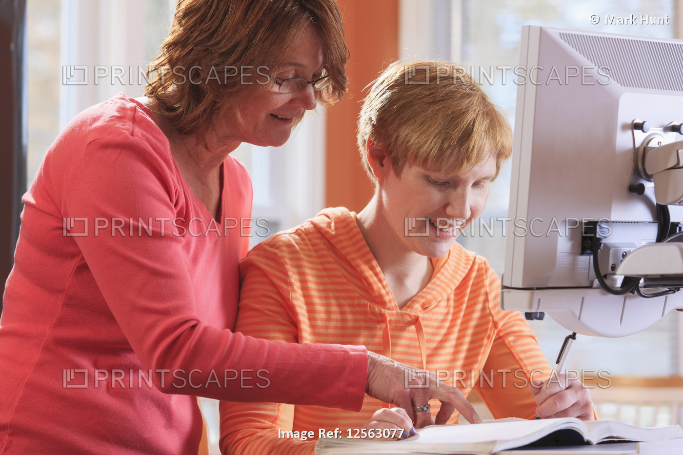 Young woman with visual impairment and her mother working at her desktop ...