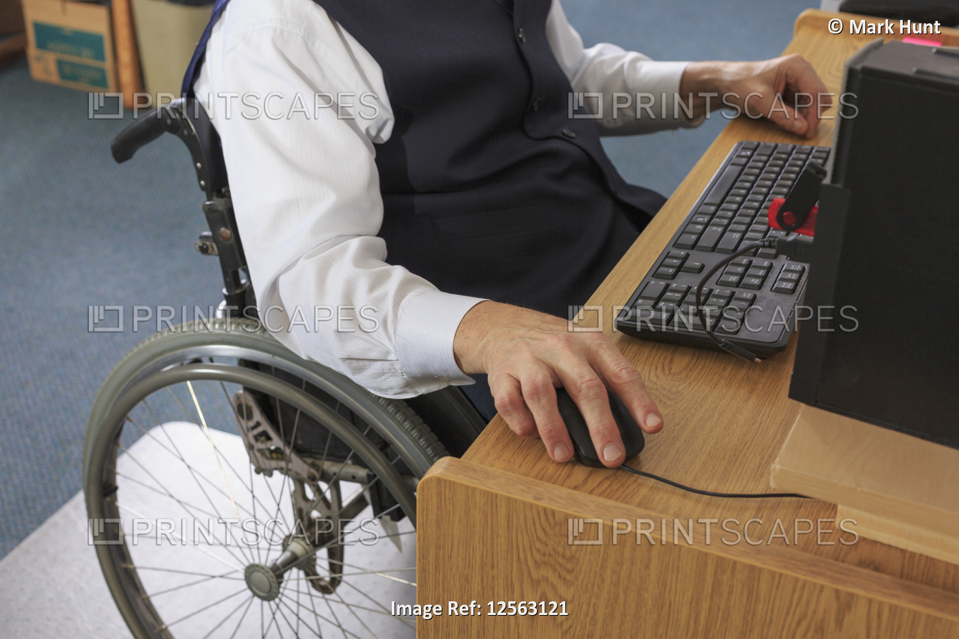 Man with Muscular Dystrophy in a wheelchair working at his computer in an office
