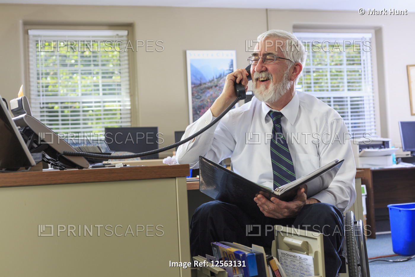 Man with Muscular Dystrophy in a wheelchair on the phone in his office