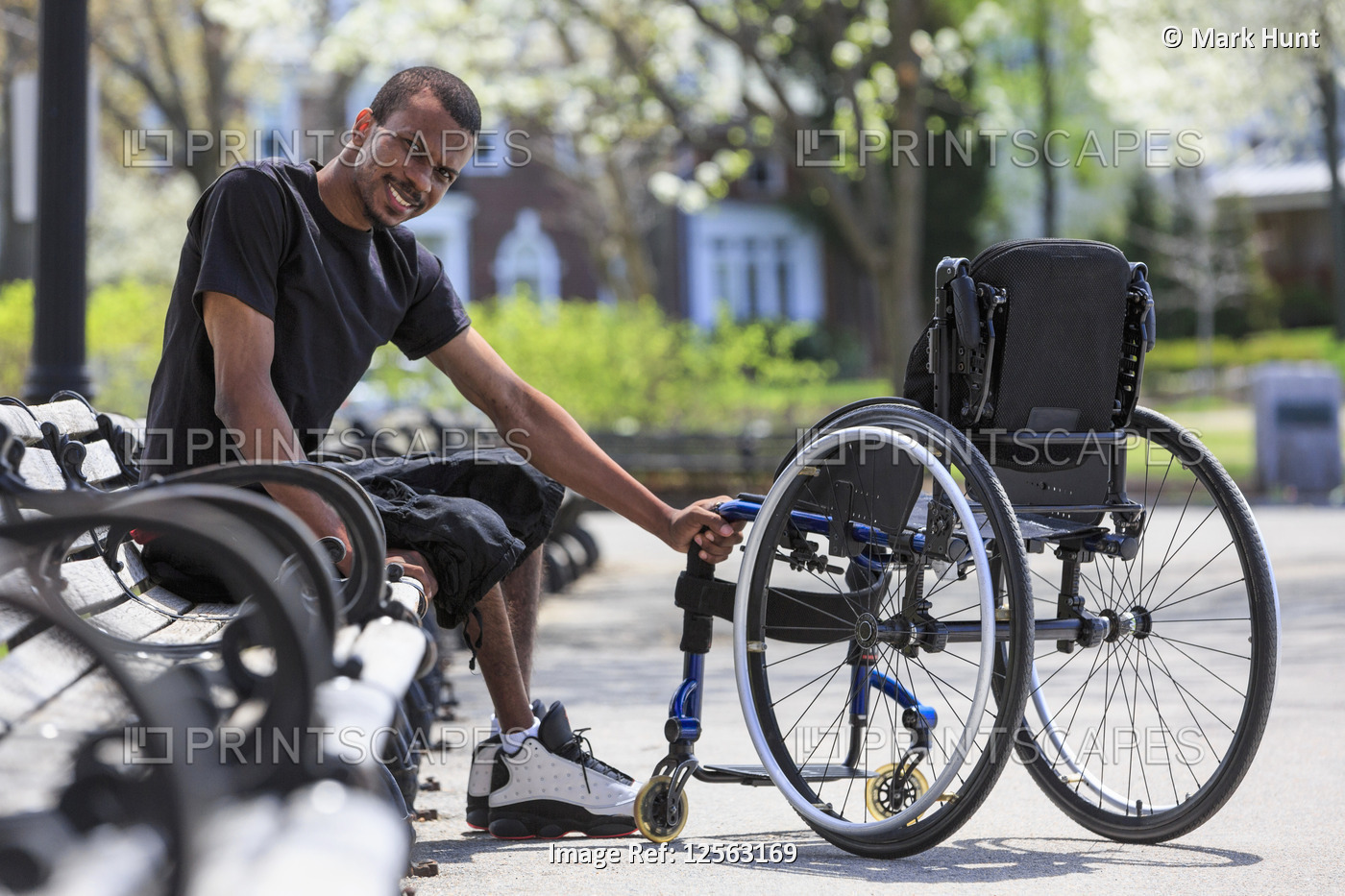Man who had Spinal Meningitis sitting on a park bench near his wheelchair