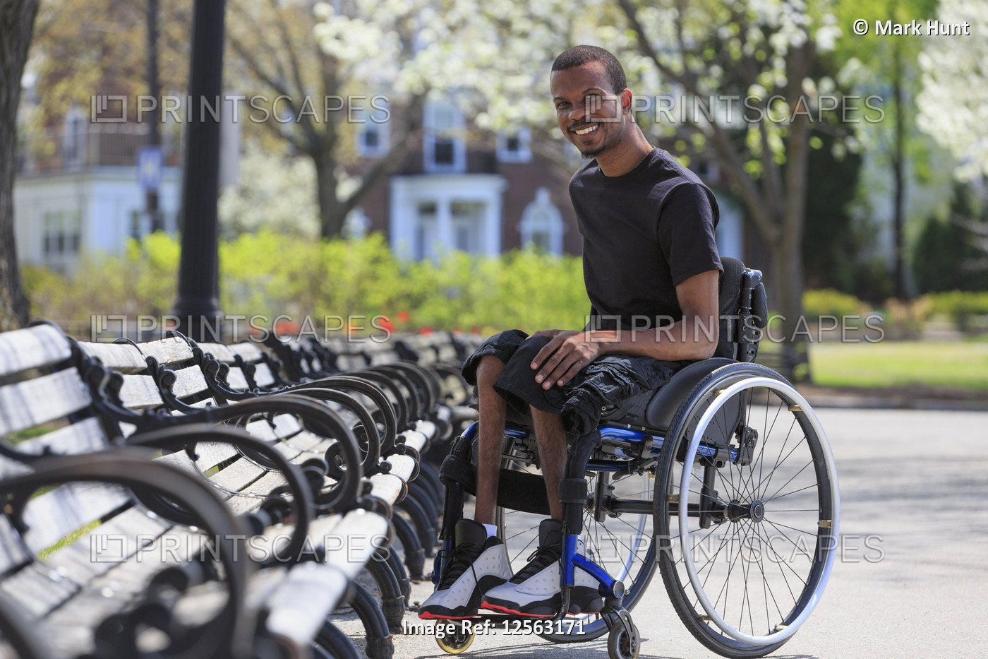 Man in a wheelchair who had Spinal Meningitis sitting near a park bench