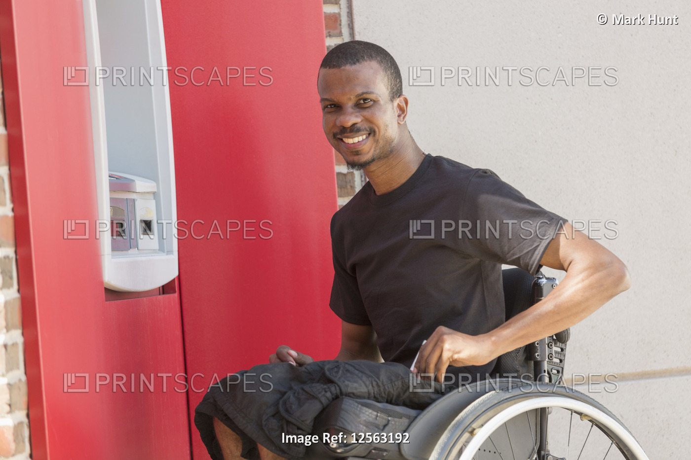 Man in a wheelchair who had Spinal Meningitis using a bank ATM