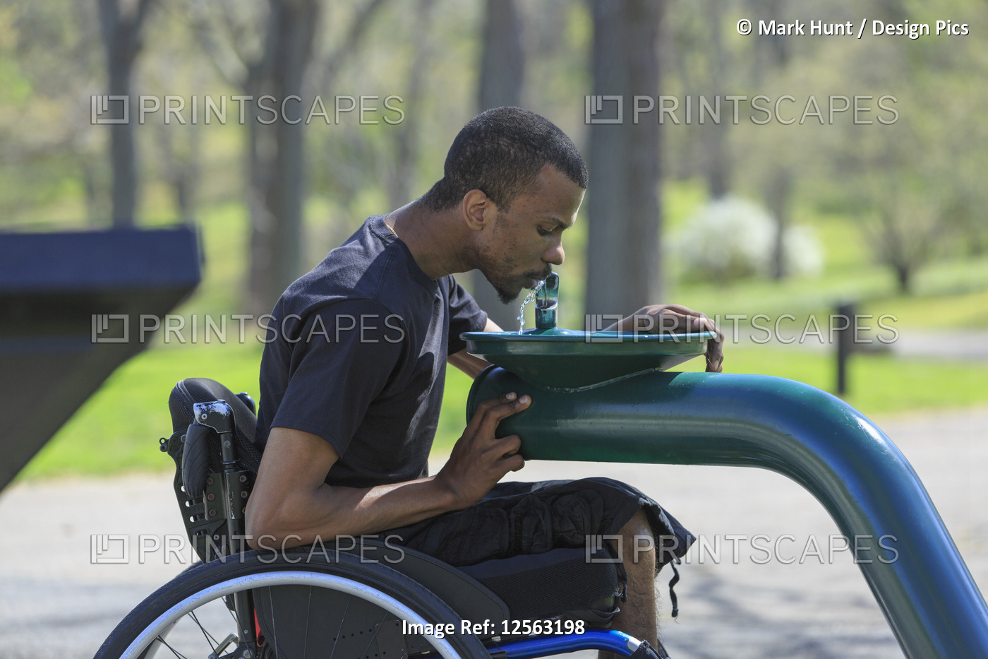 Man in a wheelchair who had Spinal Meningitis using a public water fountain