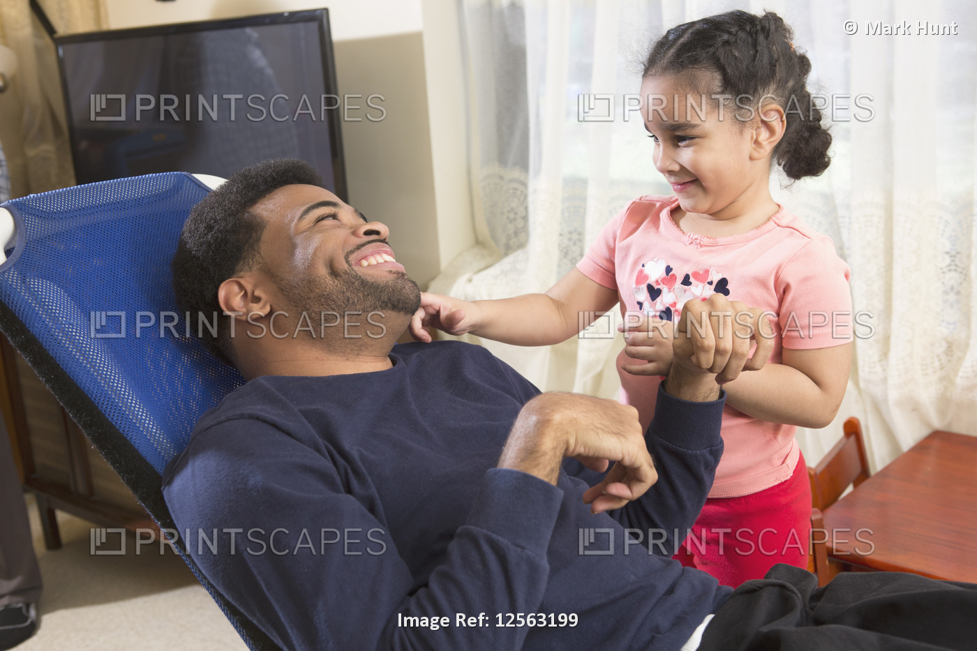African American man with Cerebral Palsy having fun with his daughter at home  ...