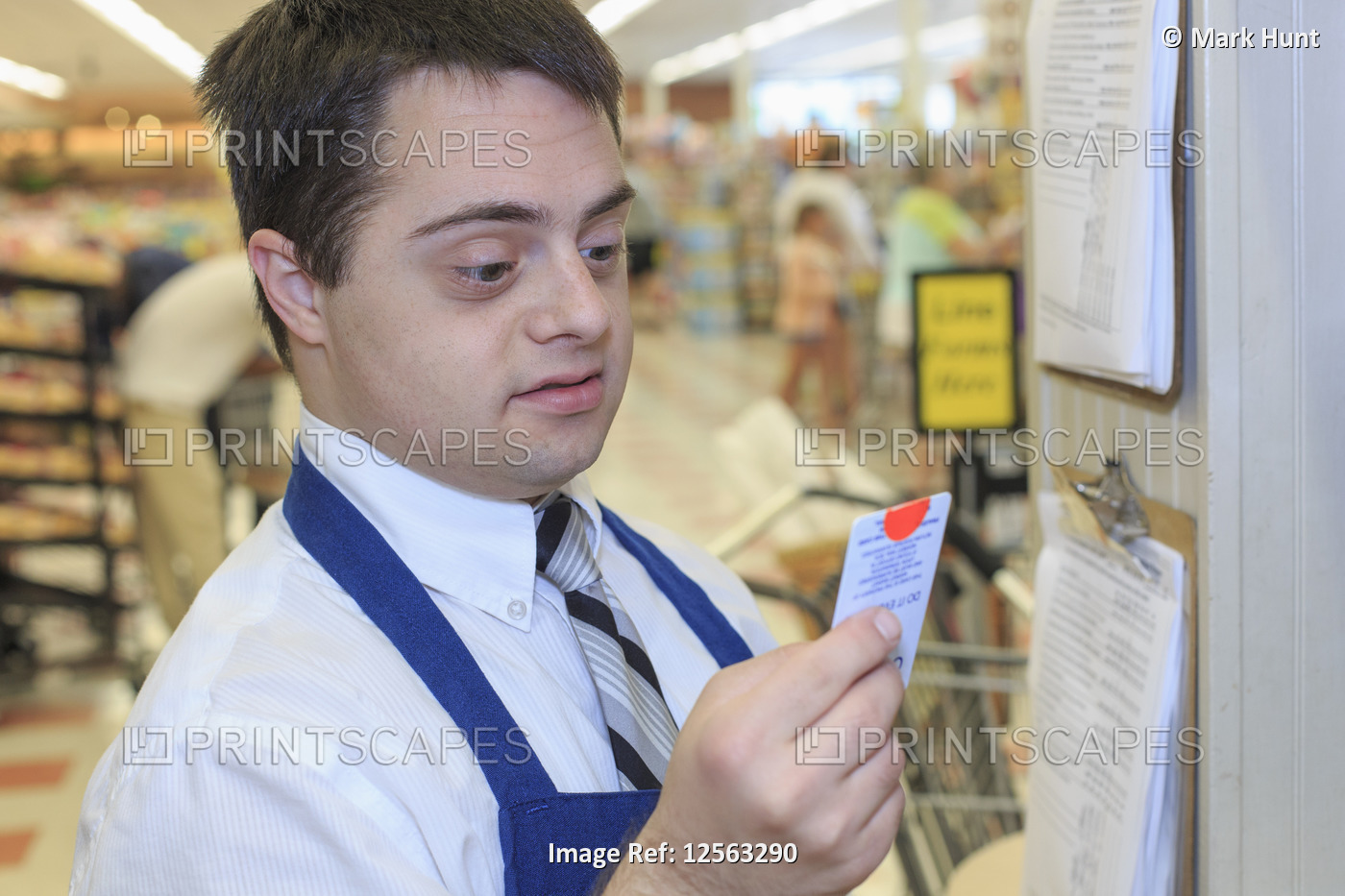 Man with Down Syndrome checking his schedule for work at a grocery store
