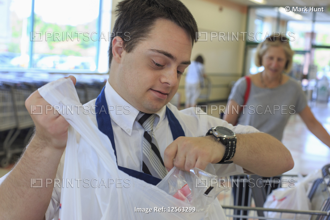 Man with Down Syndrome working at a grocery store with a customer