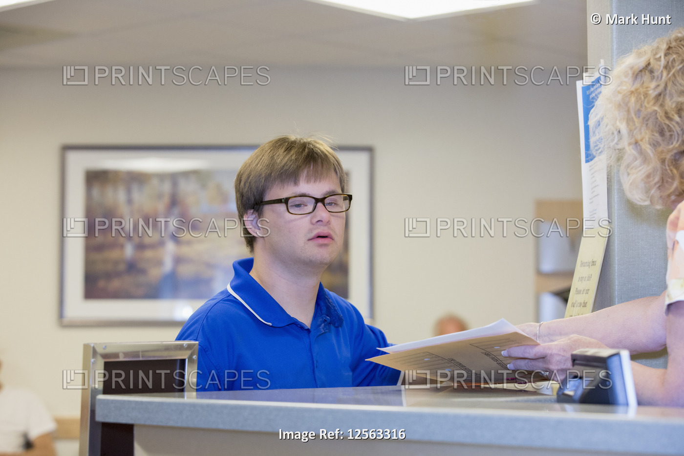 Young man with Down Syndrome taking paperwork from a nurse in a health clinic