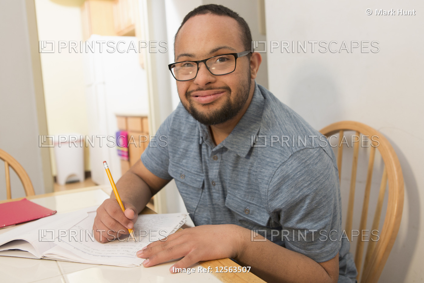 Happy African American man with Down Syndrome doing paperwork at home